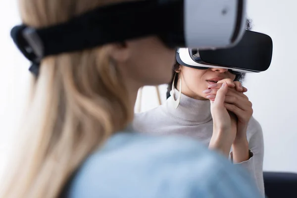 Blurred woman holding hand of african american lesbian girlfriend while gaming in vr headsets — Stock Photo