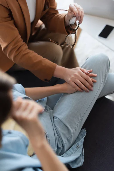 Abgeschnittene Ansicht eines Psychologen, der die Hand eines depressiven Patienten hält, verschwommener Vordergrund — Stockfoto