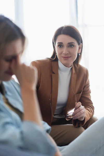 Psychologue regardant femme déprimée pleurer sur le premier plan flou — Photo de stock