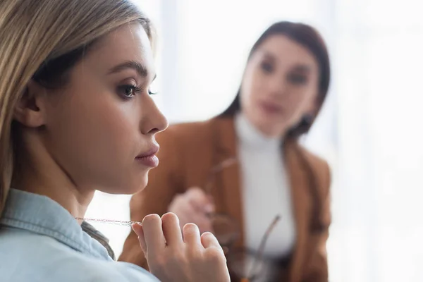 Young woman near blurred psychologist in consulting room — Stock Photo