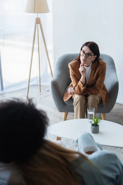 Atenta psicóloga escuchando borrosa pareja del mismo sexo en sala de consulta - foto de stock