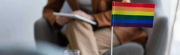 Abgeschnittene Ansicht eines verschwommenen Psychologen mit digitalem Tablet in der Nähe einer kleinen lgbt-Fahne, Banner — Stockfoto