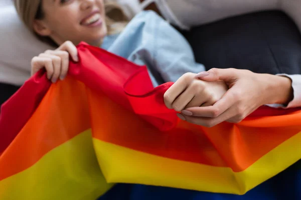 Vue recadrée de femme lesbienne tenant la main d'une petite amie floue avec drapeau lgbt — Photo de stock