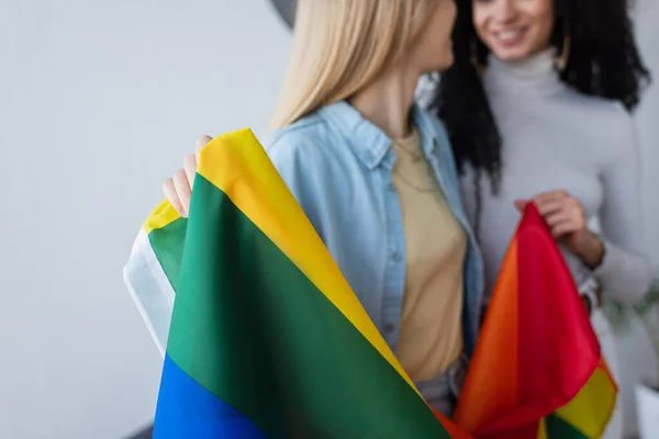 Cropped view of blurred interracial same sex couple holding lgbt flag — Stock Photo