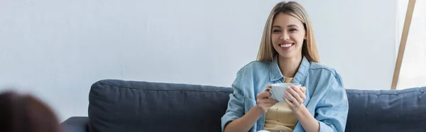 Donna sorridente che tiene una tazza di tè durante la conversazione con lo psicologo, banner — Foto stock