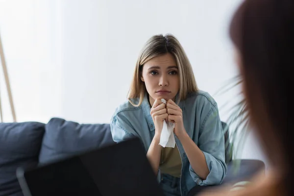 Frustrated woman with paper napkin near psychologist with laptop on blurred foreground — Stock Photo