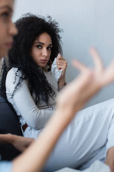 Beleidigte Afroamerikanerin sieht verschwommene Freundin an, die während psychologischer Beratung spricht — Stockfoto