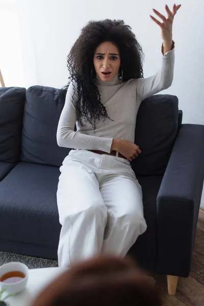 Frustrated african american woman talking and gesturing during psychological consultation, blurred foreground — Stock Photo