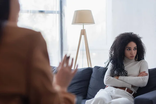 Sconvolto donna afroamericana seduta con le braccia incrociate vicino psicologo in primo piano sfocato — Foto stock