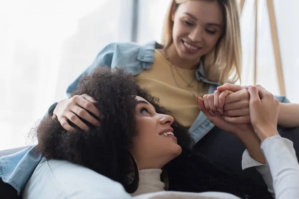 Happy interracial lesbian women holding hands and looking at each other — Stock Photo