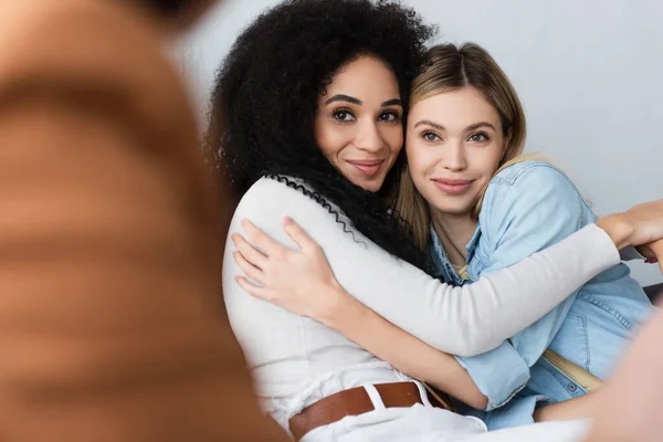 Freudige interrassische Lesben umarmen sich bei Verabredung mit verschwommenem Psychologen — Stockfoto