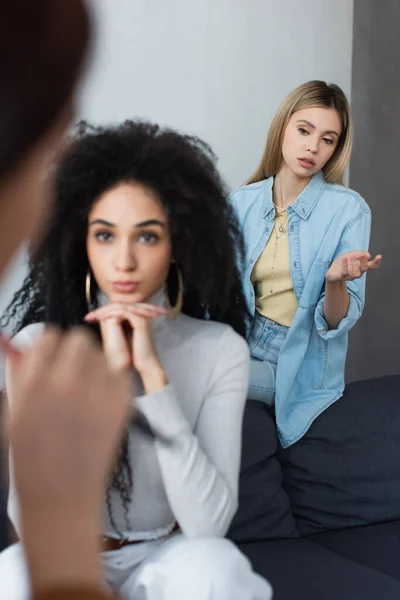 Multiethnic same sex couple listening to blurred psychologist in consulting room — Stock Photo