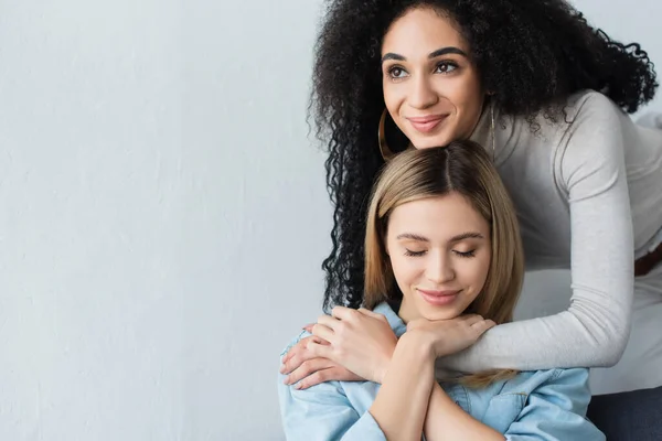 Freudige afrikanisch-amerikanische Frau umarmt lesbische Freundin beim Wegschauen — Stockfoto