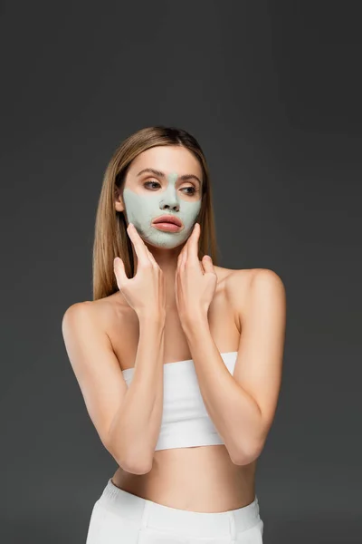 Femme en haut blanc toucher masque d'argile sur le visage isolé sur gris — Photo de stock