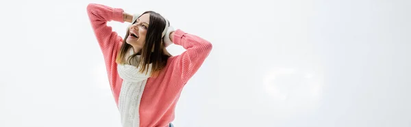Cheerful young woman adjusting ear muffs on ice rink, banner — Stock Photo
