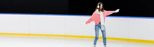 Fröhliche junge Frau mit Ohrenschützer und Schal auf der Eisbahn, Banner — Stockfoto