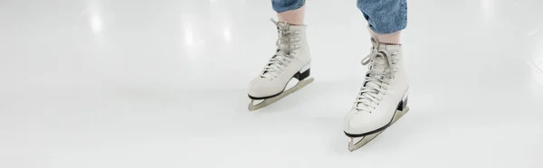 Vista recortada de la mujer en patines de hielo patinaje sobre pista de patinaje, bandera - foto de stock