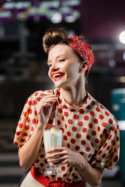 Feliz pin up mujer sosteniendo milkshake en vidrio - foto de stock