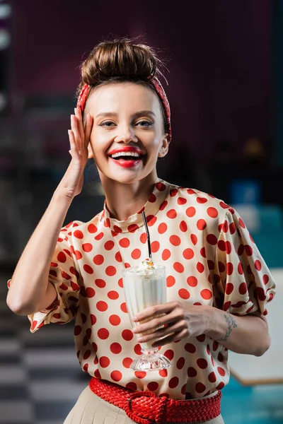 Alegre pin up mulher segurando milkshake em vidro no café — Fotografia de Stock