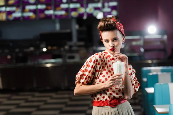 Jovem pin up mulher bebendo delicioso milkshake no café — Fotografia de Stock