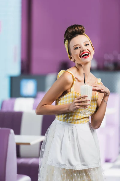 Excited pin up woman holding glass of tasty milkshake in cafe — Stock Photo