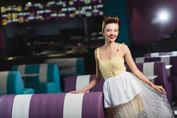 Positive Pin-up Kellnerin in gelbem Kleid steht im Café — Stockfoto