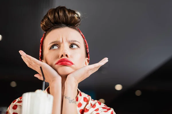 Niedrigwinkel-Ansicht einer aufgebrachten Pin-up-Frau in der Nähe von verschwommenem Milchshake — Stockfoto