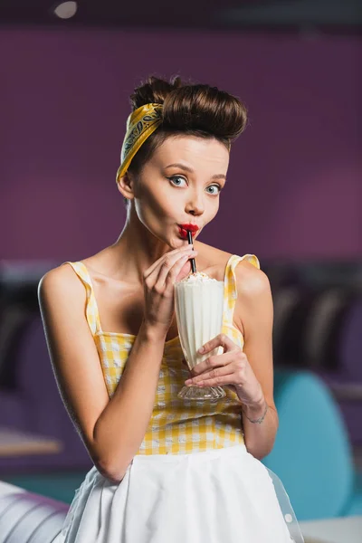 Young pin up woman drinking milkshake in vintage cafe — Stock Photo