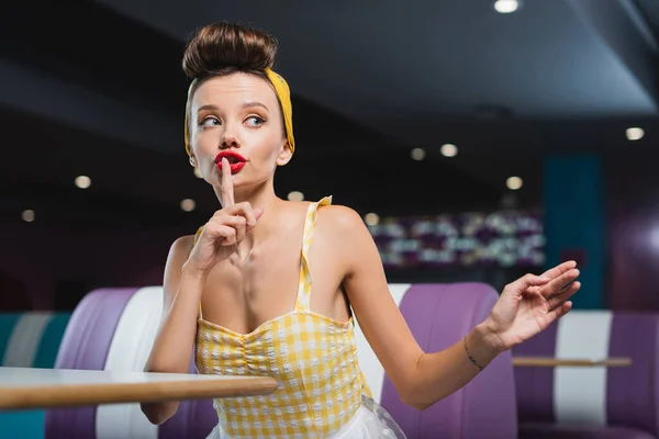 Joven pin up mujer mostrando el signo de silencio en la cafetería vintage - foto de stock