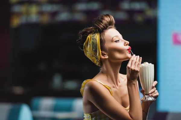 Side view of young pin up woman drinking milkshake through straw — Stock Photo