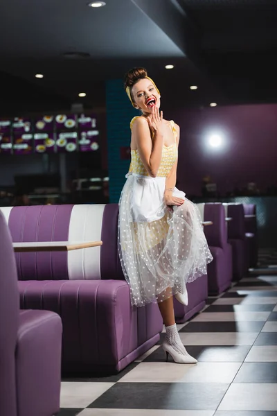 Happy pin up waitress covering mouth in retro cafe — Stock Photo