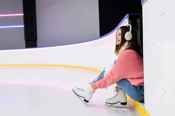 Joven sonriente mujer atando cordones de zapatos en patines de hielo - foto de stock