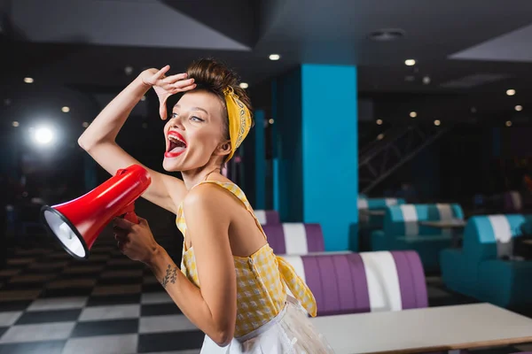 Erstaunte Pin-up-Frau schreit in Megafon in Retro-Café — Stockfoto