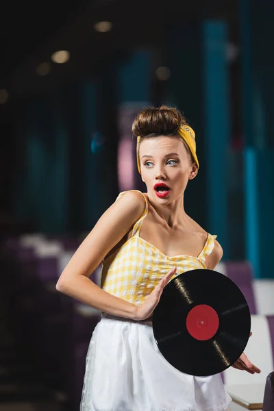 Schockierte Pin-up-Frau mit roten Lippen hält Retro-Vinyl-Scheibe — Stockfoto