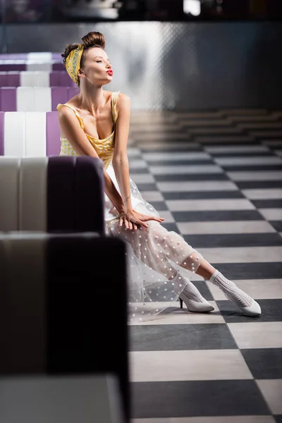 Pin up woman in dress pouting lips in vintage cafe — Stock Photo