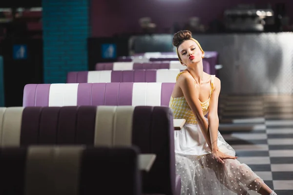 Jeune pin up femme en robe boudage lèvres dans le café vintage — Photo de stock