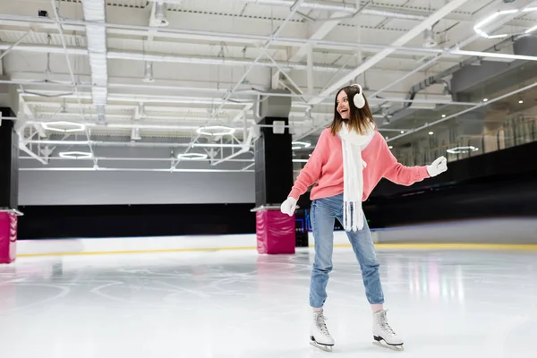 In voller Länge fröhliche junge Frau im Winteroutfit Schlittschuhlaufen auf gefrorener Eisbahn — Stockfoto