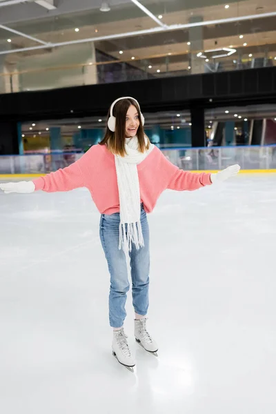 Toute la longueur de la femme étonnée en tenue d'hiver patiner sur la patinoire — Photo de stock