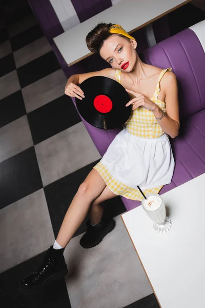 High angle view of pin up woman with red lips holding vinyl disc in cafe — Stock Photo