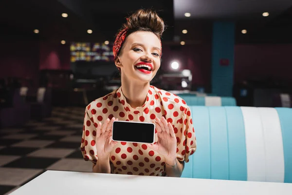 Happy pin up woman with red lips holding smartphone with blank screen — Stock Photo