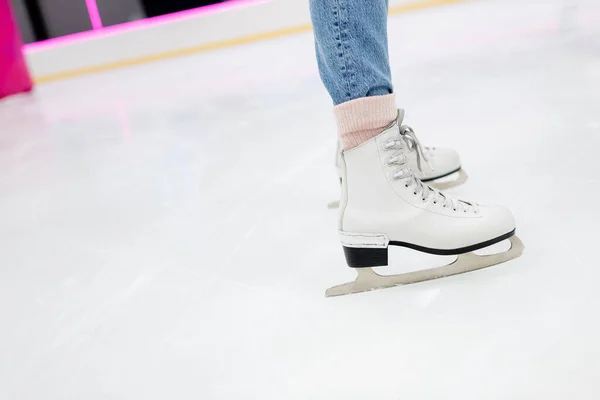 Vista cortada da mulher em patins de gelo brancos na pista congelada — Fotografia de Stock