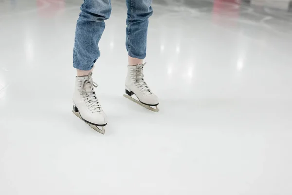 Partial view of young woman in jeans skating on ice rink — Stock Photo