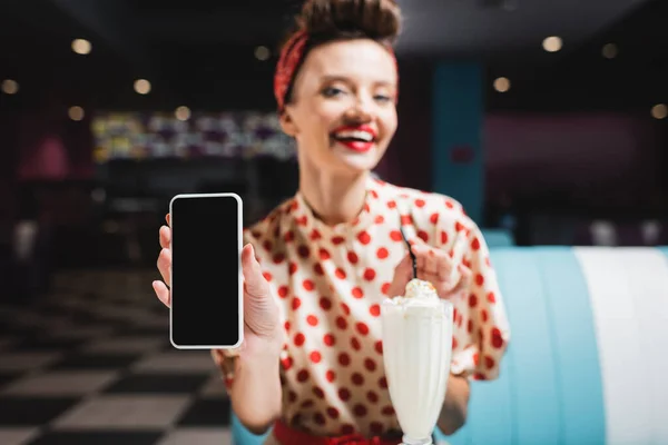 Blurred and smiling pin up woman holding smartphone with blank screen — Stock Photo