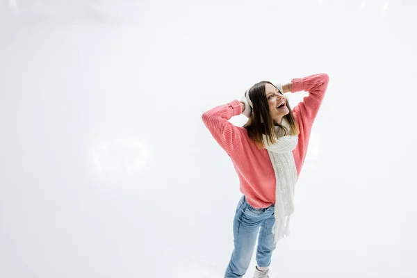 Alegre joven mujer con tatuaje patinaje y mirando hacia arriba en pista de hielo - foto de stock