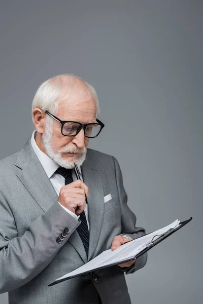 Homme d'affaires senior réfléchi dans le contrat de lecture de lunettes isolé sur gris — Photo de stock