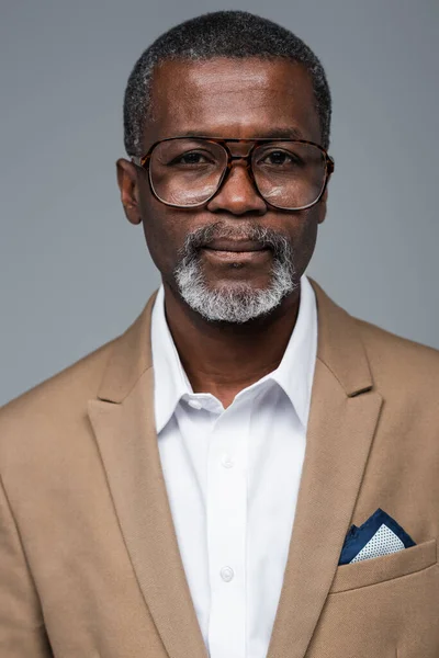 Elderly african american businessman in eyeglasses looking at camera isolated on grey — Stock Photo