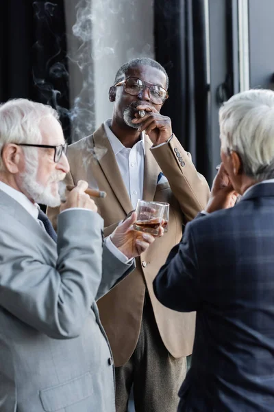 Elderly successful business partners smoking cigars and drinking whiskey in office — Stock Photo