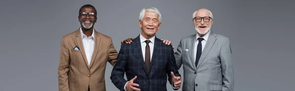Успішні високопоставлені багатоетнічні бізнесмени посміхаються на камеру ізольовані на сірому, банер — стокове фото