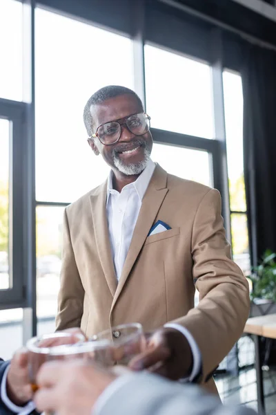 Feliz homem de negócios afro-americano óculos clinking com parceiros de negócios no escritório — Fotografia de Stock