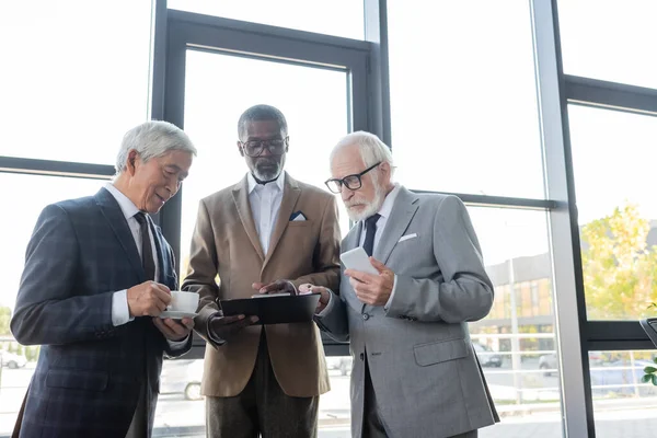 Senior multiethnic business partners discussing contract in office — Stock Photo